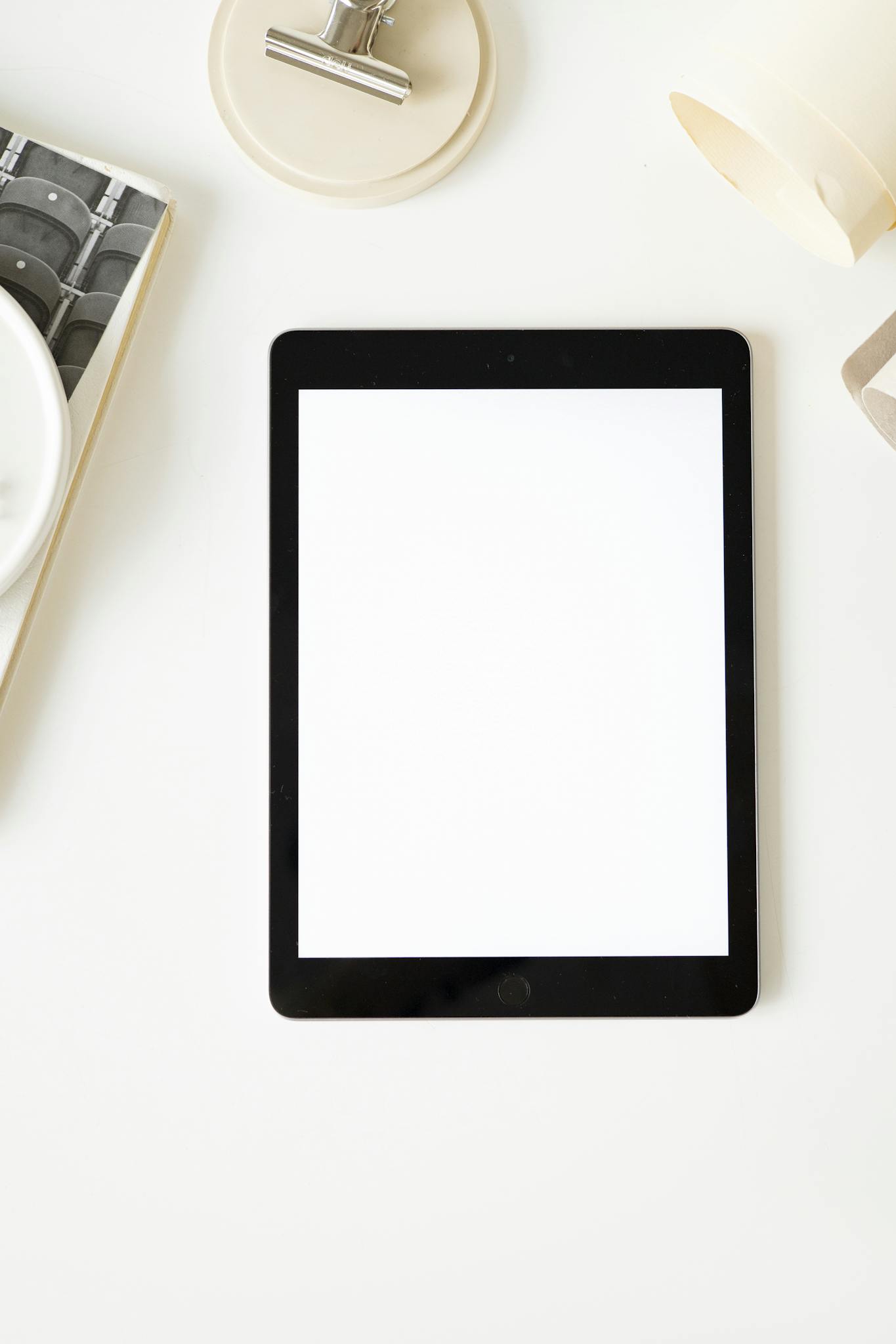 Top view of a minimalist workspace layout featuring a blank tablet screen for creative design purposes.